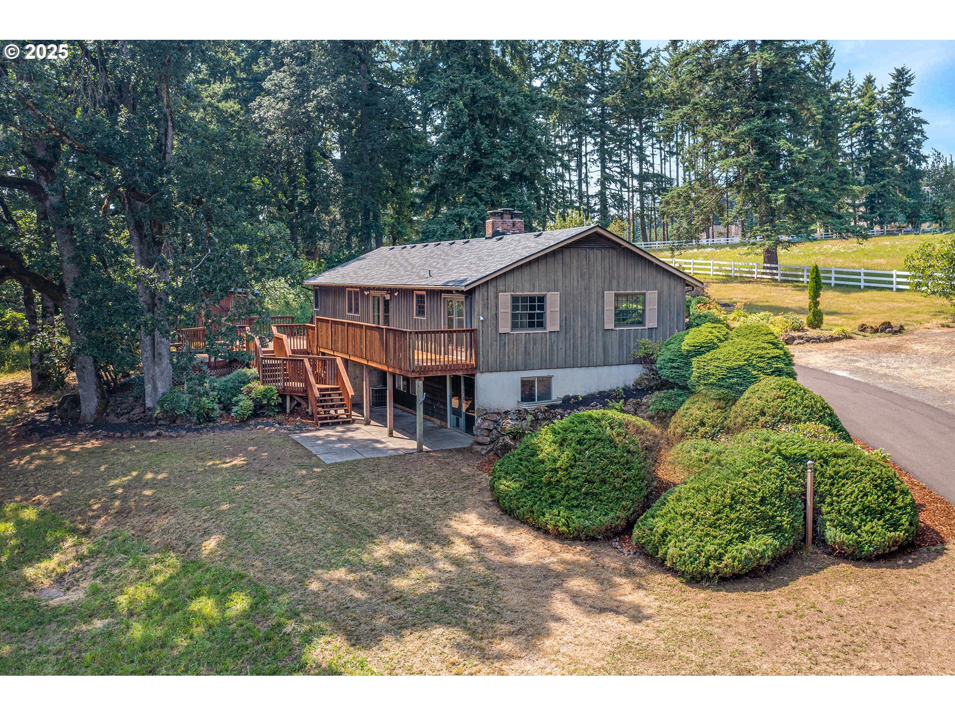 Set on over 3.5 private acres in West Linns prestigious Petes Mountain, this 3-bedroom, 2.5-bath home offers a rare combination of space, character, and opportunity. The classic brick-faced exterior and covered entry give a timeless look, while real wood floors run throughout the main level, bringing warmth and continuity to the home. Inside, two spacious living areas—each with a fireplace and brick surround—offer multiple spaces to gather and relax. The kitchen overlooks mature landscaping and opens directly to a large, multi-level deck that spans the back of the home—perfect for enjoying the view or entertaining outdoors. All three bedrooms are located on the main level, including the generous primary suite with large closets and a private ensuite. A full hall bathroom and a separate laundry room round out the main floor. Downstairs, a huge unfinished basement offers an incredible amount of potential. With a partial kitchen already started, a half bath in place, and exterior access, the space could easily be finished out for additional bedrooms, guest quarters, or extended living—ADU potential, home studio, or multi-generational living. An attached two-car garage adds everyday convenience, while the surrounding acreage provides privacy, mature landscaping with fruit trees, and space to expand. This is a unique opportunity to own a well-built home on a beautiful piece of land with room to grow—inside and out.