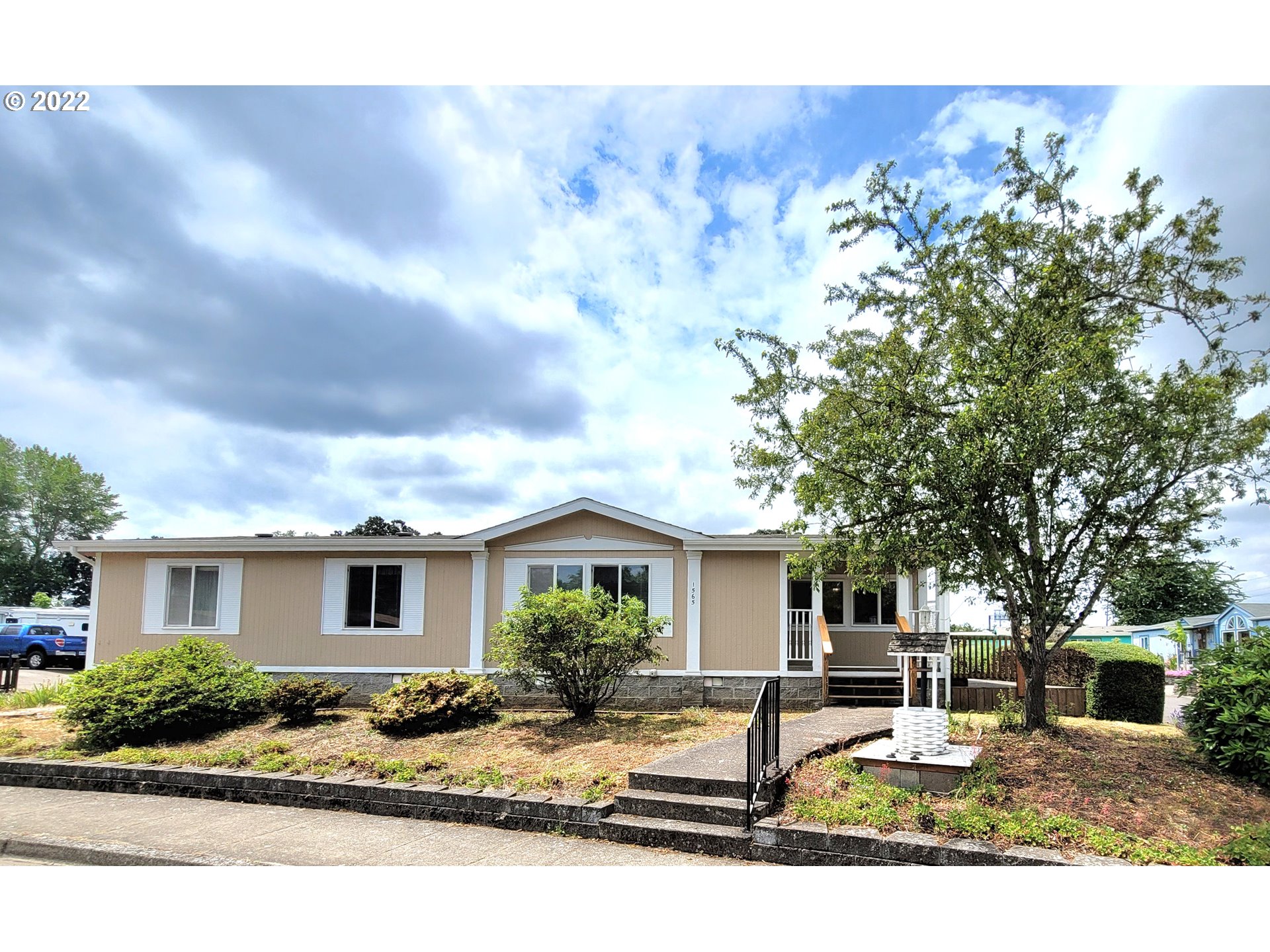 This 3 bedroom, 2 bath home is in a quiet 55+ community, but no age restriction for buyer. Large primary suite has bath w/ walk-in shower & 2 walk-in closets. Kitchen opens to dining rm is spacious w/ tons of storage & a nearly new dishwasher. Inside laundry w/ built-in storage off kitchen opens to back deck. Newly refinished ramp goes from back door to driveway. There's a 2 car garage & separate shop + 30amp RV hookup & sewer cleanout. Back deck's covered & wraps around to covered front porch.