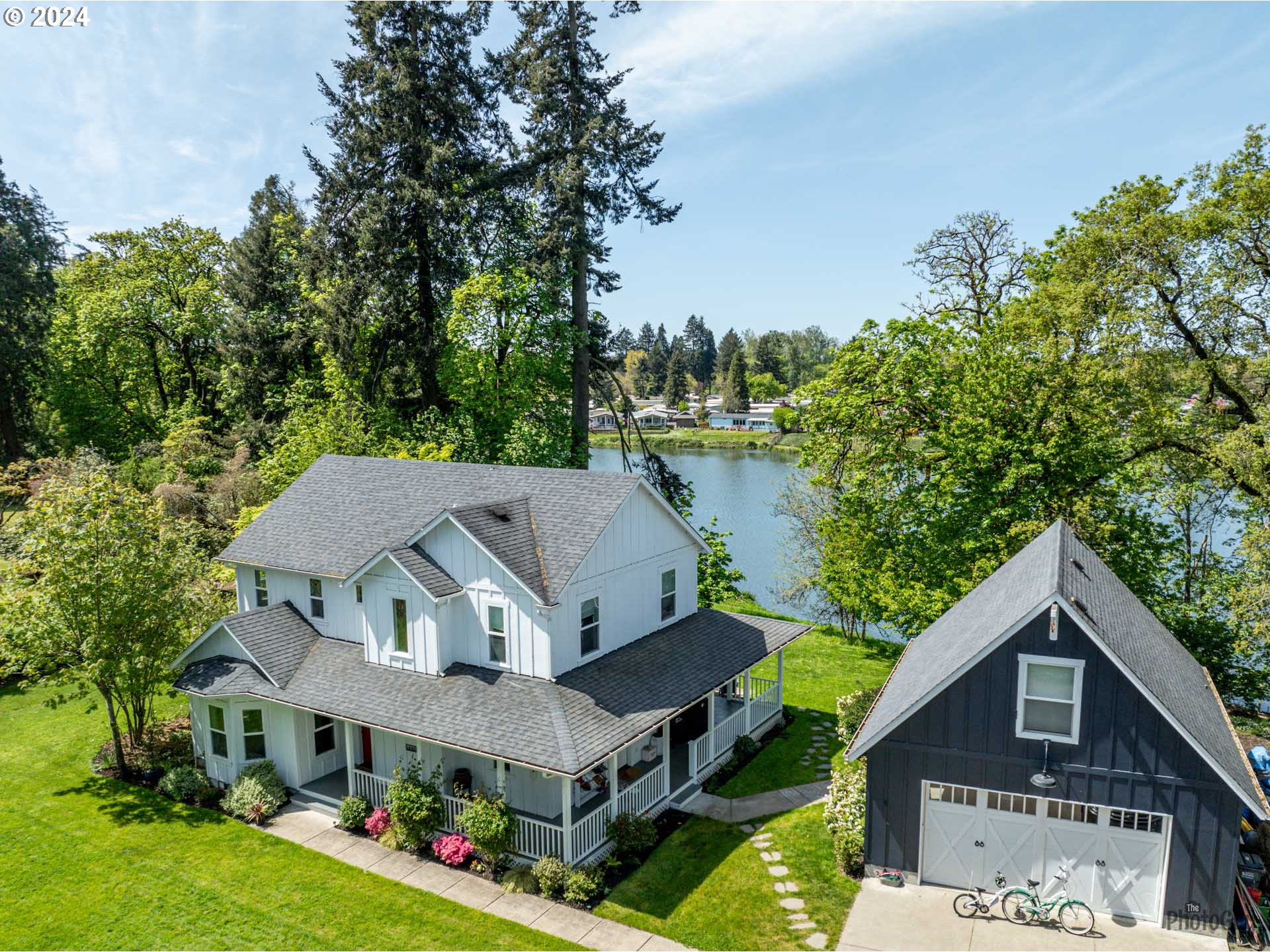 This one of a kind, 2004 built "1920's Farmhouse" is situated on 1.6 acres on Dodson Pond.  Feels like you're in Coburg but you're in North Gilham!  The residence is approached down a long private driveway.  The open, lush front yard lawn wraps all around the property.  You are greeted at the front door by a lazy and beautiful wrap around covered veranda ideal for sipping tea and cheering on the kids playing ball.  Upon entering this home, you are transported to easy living with beautiful views from every window. Gorgeous living room is just at entrance with painted wood floors and bay window.  The main living area features a large kitchen with island, craftsman cabinetry/details, lovely dining nook, island, new stainless range and hood.  The kitchen is open to family room for cozy nights warmed by vintage gas stove.  Main floor also features a bedroom which could be bedroom/office/den with full bath with clawfoot tub.  Tankless water heater for luxuriating in long, long baths...   Upstairs features two bedrooms, full bath/laundry room PLUS Primary Suite:  very large with wonderful views, circa 1920 primary bath featuring a clawfoot tub plus walk in shower, walk-in closet. The large, covered veranda on the back of home is ideal for entertaining friends and family while enjoying the most beautiful sunsets!   The extra-large garage has a finished bonus room upstairs that can be an additional flex space for working out/office/hobby!  A new staircase has been added from the backyard down to the large waterfront area of Dobson Pond ideal for paddle board, canoeing, fish (bass!) or just enjoy the ducks and geese floating by... easy country living... but you're close to everything in town!