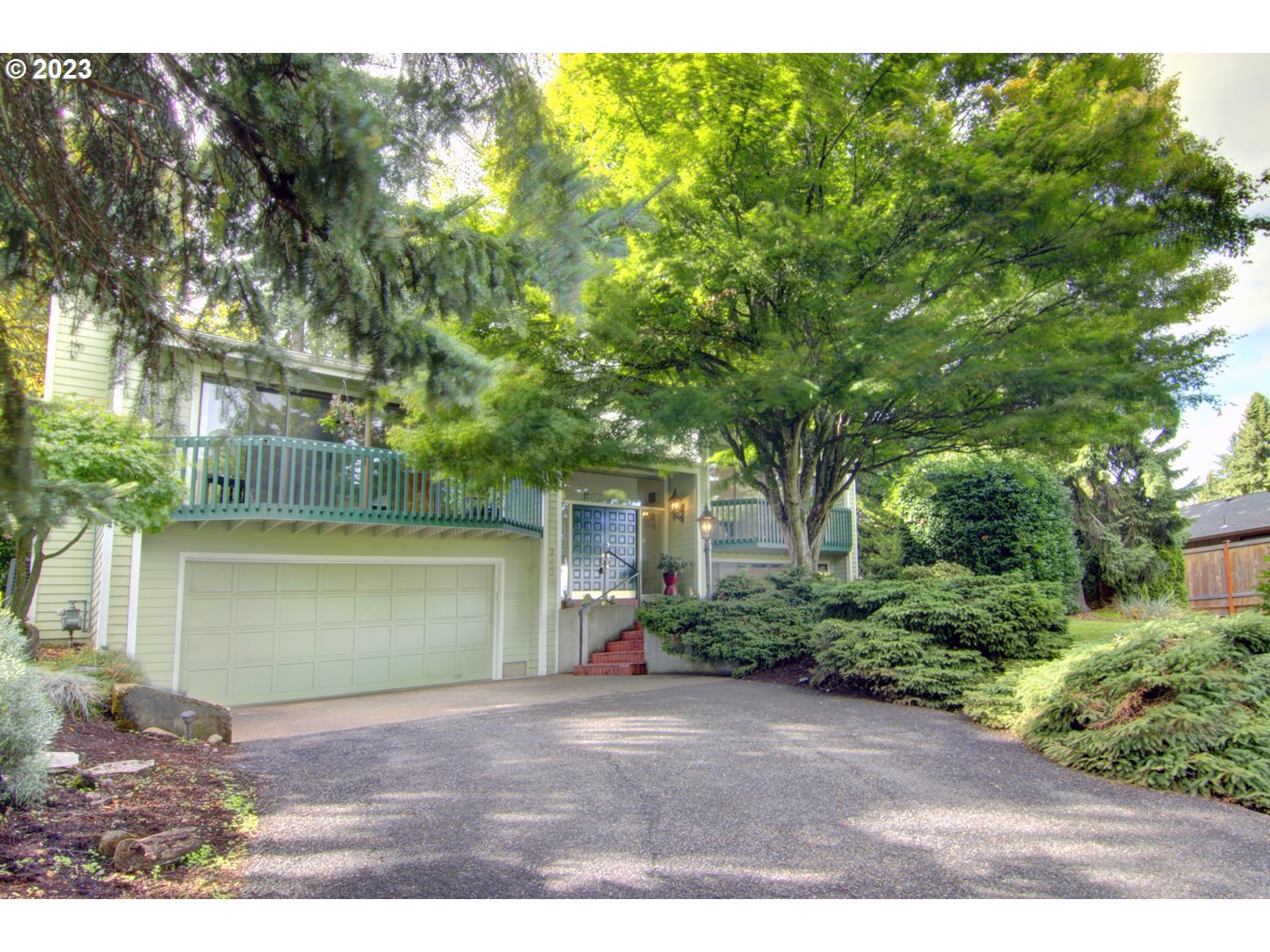 Gardeners delight with lovely living spaces and views! Amazing views from the walls of windows of the mountains and city lights. Vaulted ceilings make the home feel so spacious and a fireplace with a gas insert for cozy evenings. 1/2 acre of gently sloping land with gorgeous mature landscaping. Downstairs primary suite with jetted tub. New roof just installed. Heat pump serviced regularly. Irrigation system for raised beds. Sunny deck over looking the large, fenced backyard. The home is placed well back from the street for a very private feeling. Large extra deep 2 car garage with space for storage or a shop. Come watch the dahlias bloom in your new home!