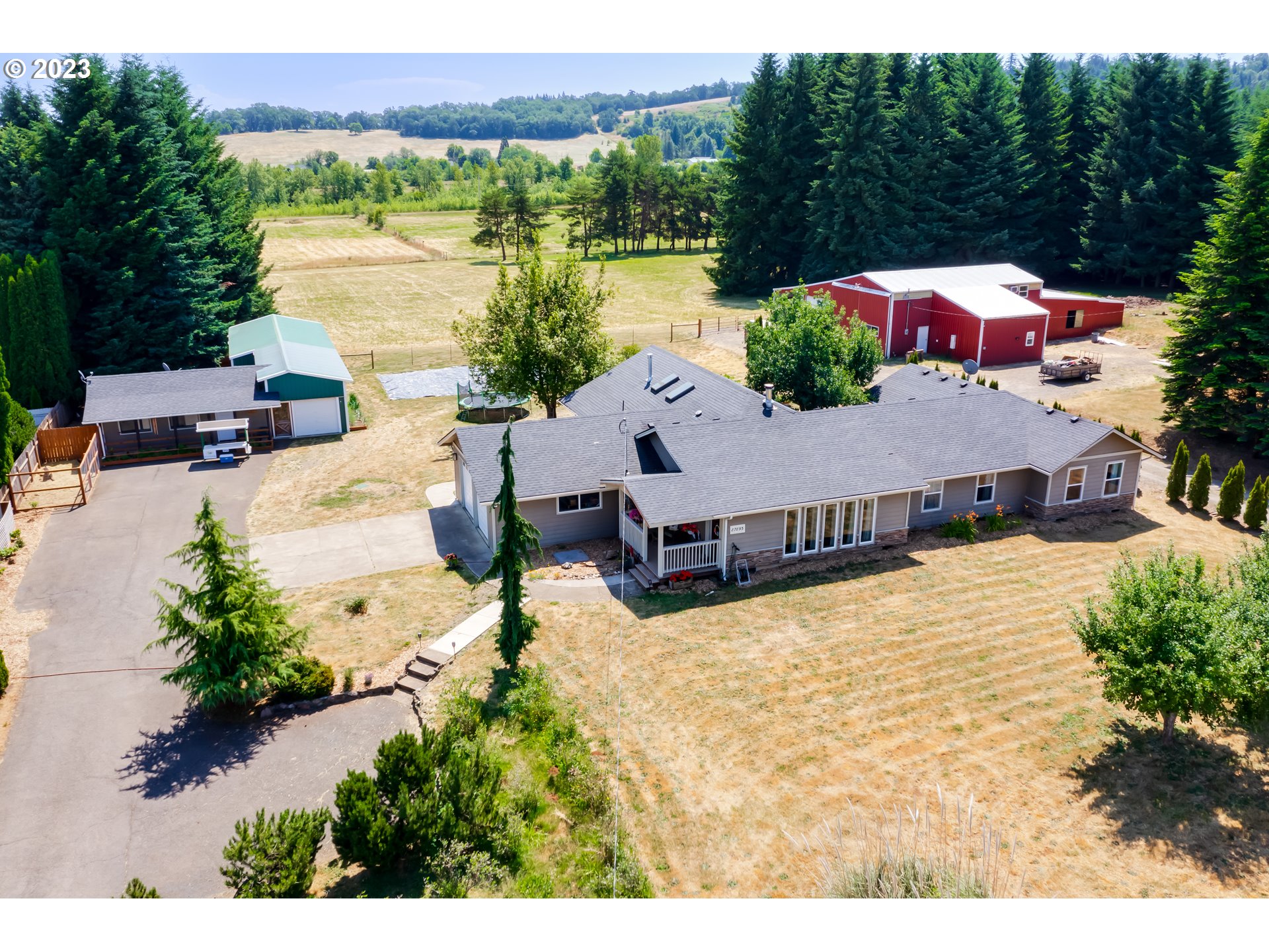 Close-in country living! Perfect hobby farm! This level 5 acre property has a 2556 sqft remodeled one level home, enormous barn and shop with multiple uses. The lovely home offers a great room concept with kitchen and dining rooms surrounding a central soapstone custom fireplace. An abundance of cabinetry and counter space is available including an island with an eating bar, stainless steel appliances and propane range. Engineered hardwood floors run throughout the home including the living room with wood plank vaulted ceilings, a propane fireplace and French doors to the covered deck. Both bathrooms have been updated which include wood slab and granite counters, dual flush toilets, tile showers and a gorgeous soaking tub. The primary bedroom has a roomy walk-in closet which can be accessed from the 15'x15' 4th bedroom. One of the outbuildings offer a shop, art studio, canning kitchen (previously ceramics studio), chicken coop and more. The 4500 sqft insulated and heated barn/shop has a compressor, 1 ton hoist, exhausted paint room, hay storage and much more.  Don't miss the 50 blueberry bushes and cozy wooded area with a fire pit. A must see!