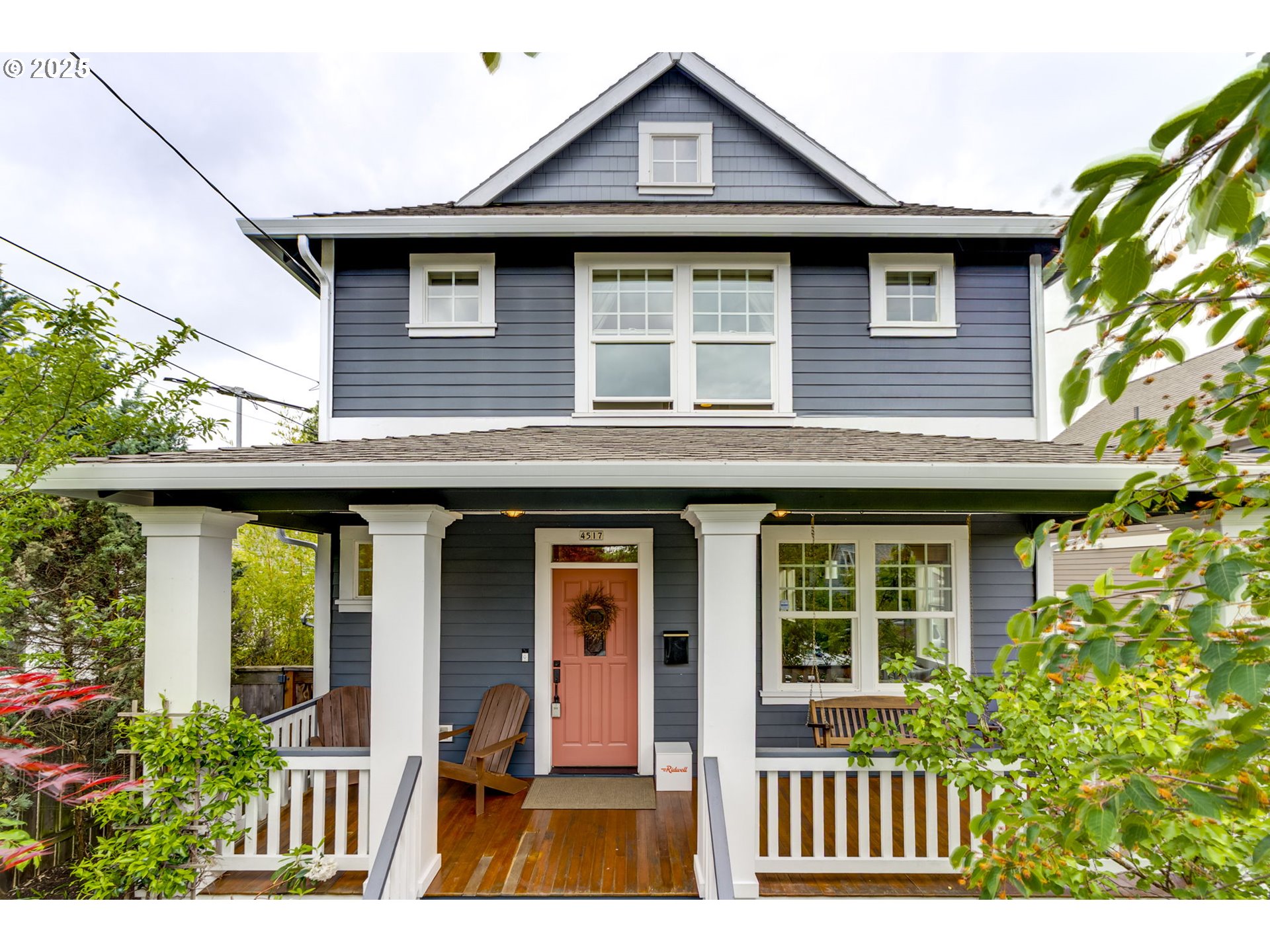 Modern living meets classic style in this thoughtfully built 2006 home. Designed to blend seamlessly into a neighborhood of vintage houses, this newer build offers the best of both worlds: modern comforts wrapped in timeless design. A spacious front porch with wood decking and stately columns invites morning coffee and friendly chats with neighbors. Inside, rich wood floors, craftsman-style trim, a formal entryway, and a handsome fireplace with built-ins bring warmth and character. The open-concept layout offers a circular flow through the living room, dining area, and spacious kitchen with a central island, ideal for gathering and staying connected. Generous windows on all sides fill the home with natural light. A versatile sunroom and mudroom space on the main floor works perfectly as a drop zone, reading nook, or home office. Upstairs, the primary suite features a beautifully tiled bath with heated floors and walk-in closet. Two additional bedrooms overlook the backyard and share a second full bath. Convenient upstairs laundry makes daily life easier! Out back, mature landscaping surrounds a deck and patio that extend your living space and invite alfresco dining and entertaining. A long driveway offers ample off-street parking, and the garage is ideal for storage, hobbies, or parking. With a Bike Score of 100 and Walk Score of 83, you're perfectly positioned to enjoy Portland’s community lifestyle. Just blocks from the vibrant Alberta Arts District, you'll have easy access to great restaurants, coffee shops, boutiques, and neighborhood events. Move in, unpack, and go play!